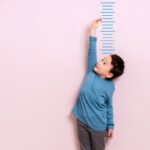Child measures his height on wall. He is growing taller.